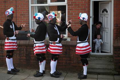 Miembros de los Britannia Coconut Dancers of Bacup, con rostros ennegrecidos para evitar ser reconocidos por los espíritus malignos, participan en su Procesión Límite anual del Sábado de Pascua en Bacup, cerca de Manchester, en el noroeste de Inglaterra, el 8 de abril de 2023.