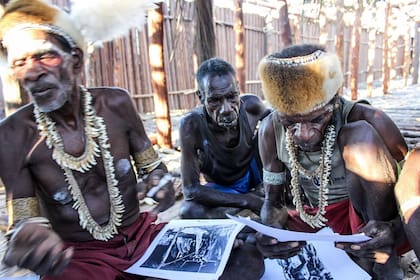Miembros de tribus Asmat observan fogografías que sacó Michael Rockefeller en su paso por la isla de Papúa Nueva Guinea en 1961