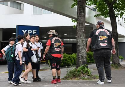 Miembros del capítulo chileno de los Hells Angels conversan y posan con estudiantes frente a una estación de servicio en el centro de La Plata