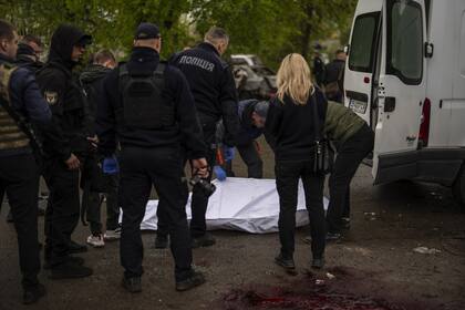 Miembros del equipo forense y policial retiran el cuerpo de una mujer muerta después de un bombardeo ruso en Chernihiv, Ucrania, el miércoles 17 de abril de 2024.
