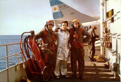 Miembros del personal auxiliar de pista en el pasillo de estribor de la isla; al fondo, la cola de un avión A4 Skyhawk