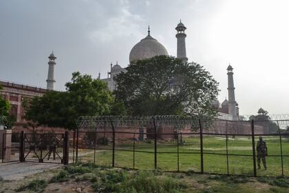 Miembros del personal de seguridad montan guardia detrás de una valla perimetral en el Taj Mahal