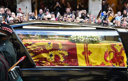 Miembros del público observan el paso de la carroza fúnebre que lleva el féretro de Isabel II