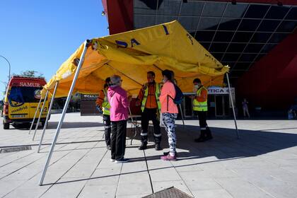 Miembros del Servicio de Emergencias Médicas de Madrid bajo una carpa frente a un centro de información en Madrid