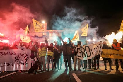 Miembros del sindicato de agricultores Confederation Paysanne sostienen pancartas durante una acción destinada a ralentizar el tráfico de tractores en la circunvalación de París, a la altura de Porte de Montreuil, para presionar al gobierno francés a que bloquee el acuerdo comercial con Mercosur y protestar contra su gestión de la epidemia de dermatitis nodular contagiosa (DNC), en París, el 9 de enero de 2026.