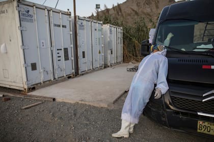 El trabajador funerario, Angelo Aza, de Venezuela, descansa junto a containers que contienen cuerpos refrigerados, junto a un hospital de Lima