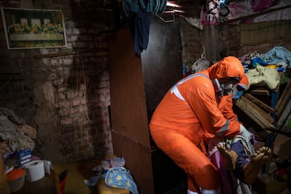 Los trabajadores de la funeraria Jhoan Faneite y Luis Brito, ambos de Venezuela, extraen el cuerpo de un carpintero retirado de 85 años que se sospecha que murió por complicaciones debido al nuevo coronavirus, en el barrio de Chorrillos, en Lima