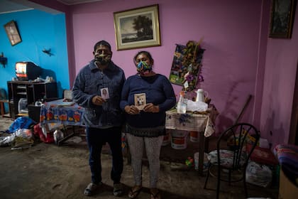 Los hermanos Jorge y Julia López muestran fotos familiares en la sala de estar donde su padre Faustino López se suicidó después de enterarse de que había dado positivo por el nuevo coronavirus, en Lima, Perú
