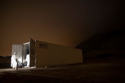 Trabajadores de la salud trasladan un cuerpo dentro del container refrigerado