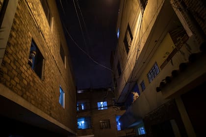 Vecinos observan cómo los trabajadores de la funeraria Piedrangel extraen el cuerpo de una persona sospechosa de morir por coronavirus, en un barrio de Lima