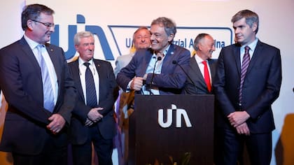 Mientras Peña observa, Cabrera le sonríe a Kaufmann antes de leerle la lista de medidas reclamadas por la UIA