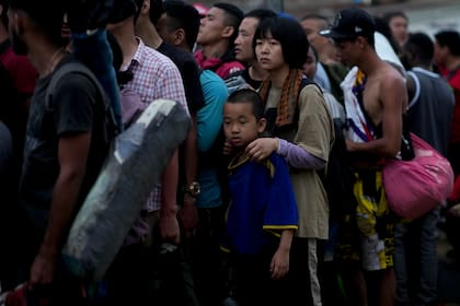 Migrantes chinos hacen fila para abordar una embarcación hacia Lajas Blancas después de cruzar a pie la selva del Darién, el domingo 7 de mayo de 2023, en Bajo Chiquito, Panamá (AP Foto/Natacha Pisarenko)