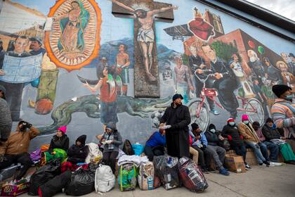 Migrantes comen y esperan ayuda, acampados en una calle del centro de El Paso, Texas, 18 de diciembre de 2022