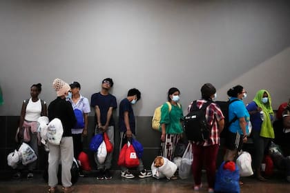 Migrantes, en su mayoría de países asiáticos, esperan el transporte a los hoteles después de llegar a Ciudad de Panamá el 8 de marzo de 2025, después de pasar semanas en un campamento temporal de inmigración panameña tras su deportación de EEUU y ser liberados con la condición de que abandonen el país dentro de los 30 días.