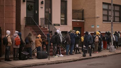 Migrantes esperan en el frío para encontrar refugio fuera del centro de asistencia en la escuela primaria St. Brigid, el 5 de diciembre de 2023, en Nueva York.