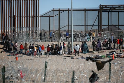 Migrantes formados después de ser detenidos por las autoridades migratorias de Estados Unidos en el muro fronterizo, en una imagen captada desde Ciudad Juárez, México. (AP Foto/Christian Chavez)