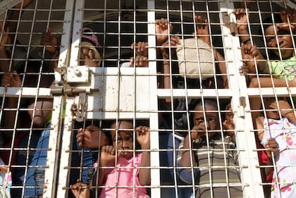 Migrantes haitianos miran desde un vehículo policial entre República Dominicana y Haití mientras esperan ser deportados