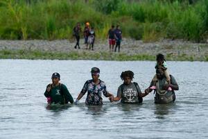 Migrantes haitianos vadean el río Tuquesa después de caminar por el Tapón del Darién, el miércoles 4 de octubre de 2023, en Bajo Chiquito, Panamá (AP Foto/Arnulfo Franco, Archivo)