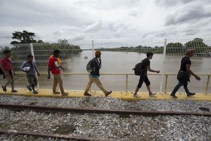 Migrantes hondureños caminan por el puente fronterizo entre Guatemala y México