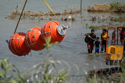 Migrantes observan la instalación de las boyas gigantes (AP Foto/Eric Gay)