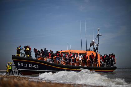 Migrantes, recogidos en el mar al intentar cruzar el Canal de la Mancha, son ayudados a desembarcar desde un bote salvavidas de la Royal National Lifeboat Institution (RNLI) en Dungeness, en la costa sureste de Inglaterra, el 15 de junio de 2022.