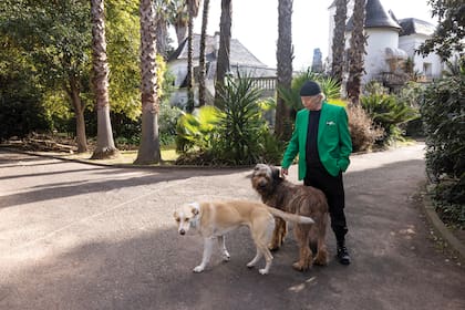 Miguel Romano juega con Nina y Tito, dos de sus mascotas. Detrás, entre las palmeras, su casa, que compró hace cuarenta y cinco años.