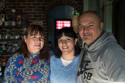 Milagros González junto con sus papás en el living de su casa en Merlo.