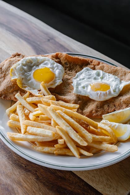 Milanesa con papas y huevos fritos.