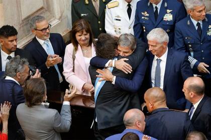 Milei abraza a Luis Caputo, su ministro de Economía, durante la apertura de las sesiones legislativas; ambos cuidan el ajuste del Estado