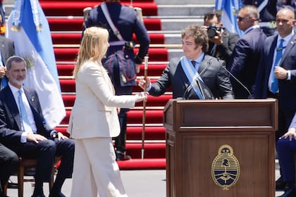 Milei y su hermana Karina con el bastón presidencial, de espaldas al Congreso, ante la mirada del rey Felipe de España