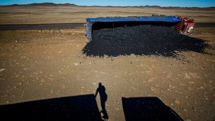 Un fotógrafo proyecta su sombra cerca de un camión de carbón que volcó en Khanbogd Soum