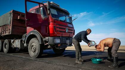 Un conductor de camión se lava con agua embotellada en la carretera principal para entregar carbón a China en Khangobd Soum en el desierto de Gobi