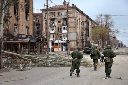 Milicianos de la República Popular de Donetsk caminan junto a edificios de apartamentos dañados, el sábado 16 de abril de 2022.