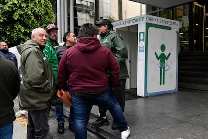 Militantes del gremio de Camioneros, en la puerta de la sede allanada; entre ellos Patón Basile (de verde, con la cara tatuada)