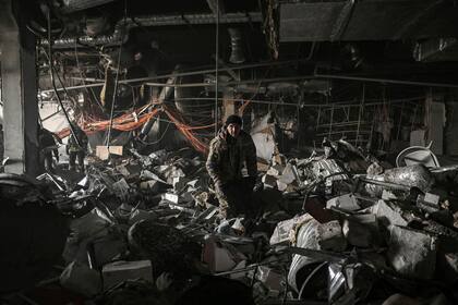 Militares ucranianos buscan entre los escombros dentro del centro comercial Retroville después de un ataque ruso en el noroeste de Kiev, el 21 de marzo de 2022