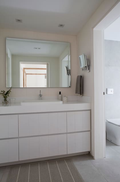 Minimalista al extremo, en el antebaño, el vanitory se diseñó a medida con cajones, y mesada y bachas de Corian. Grifería de Hansgrohe