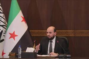 Mohamed al Bashir, el primer ministro del nuevo gobierno de transición de Siria, junto a la controvertida bandera