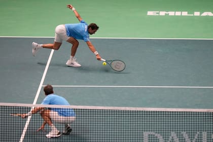 Molteni intenta llegar a una bola desde el fondo; Zeballos observa desde la red