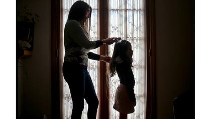 Monica Flores peina el cabello de su hija en su casa en Santiago, Chile.
