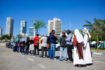 Monjas, solicitantes de asilo y trabajadores extranjeros esperan en fila para recibir su primera dosis de la vacuna contra el coronavirus de Pfizer-BioNTech en un centro de vacunación en Tel Aviv, Israel