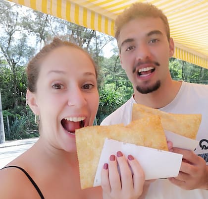Monserrat y Mateus saborean una especie de empanada frita, comida típica brasileña.