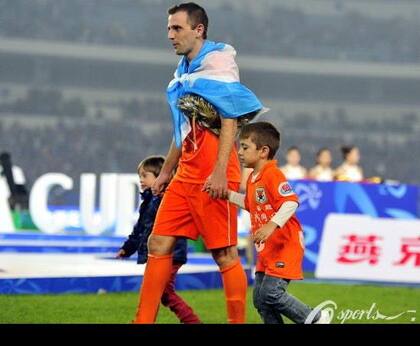 En China, Montillo ganó dos títulos y festejó uno con una bandera argentina y con sus hijos en el campo de juego.