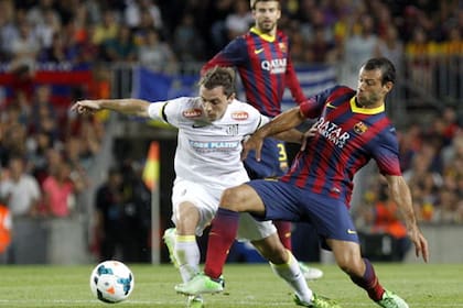 Montillo, con la camiseta de Santos, enfrentándose con Javier Mascherano y Gerard Piqué, en un amistoso frente a Barcelona.