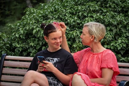 Mother discusses with rebellious teenage daughter in the park - problems of parents in relationships with children in adolescence.