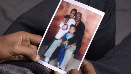 Moti Dereje con una vieja fotografía familiar de él y su hermano menor cuando eran niños con su padre