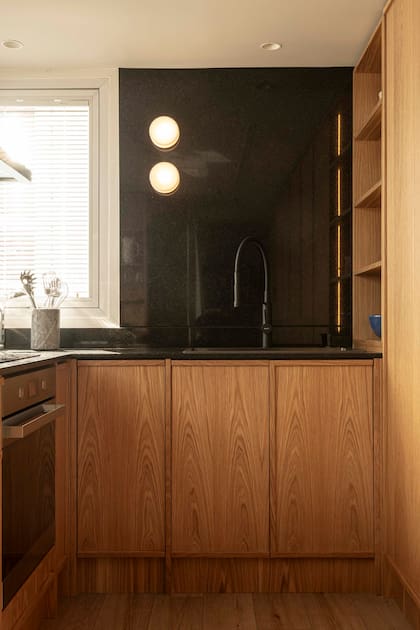 Mueble bajomesada y muebles de roble americano (todo diseñado a medida por Alejandra Nusenovich). Mesada de granito 'Negro Brasil'. Apliques de pared (Huup).