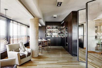 Mueble de bar de nogal lustrado (diseño Estudio Licia Falicoff realizado por Solotar). Mesa con sillas de cuero negro gastado y biombo ‘Metro’ de espejo envejecido (todo de Paul French Gallery). Spots (Fábrica de Luz). Persianas americanas de madera negra (Riel Americano). Actualizaron las butacas que tenían con almohadones de cuero.