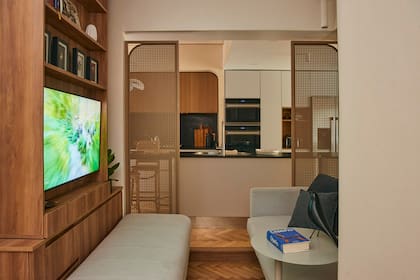 Mueble de TV hecho en melamina ‘Scotch’ de Faplac (Vint Market). Sillón (CDI). Las puertas de hierro esterilladas (Vint Market) permiten abrirlo o cerrarlo y, también, poder supervisar desde la cocina a los chicos que miran la tele.