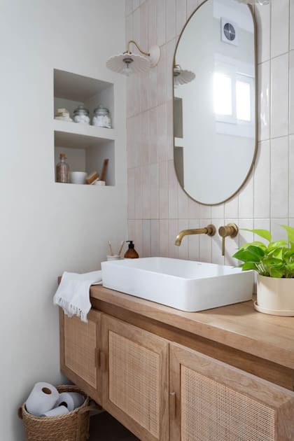 Mueble en madera de kiri y esterilla americana (Casa Perri). Bacha ‘Embarcadero’ (Ponthus). Grifería cromada (Grifos Ya). Espejo (Aldea Lobos). Apliques ‘Rita’ en cerámica y bronce (Margarita de Forteza). Revestimiento ‘Gemstone Cream’ (Syria Cerámicos).