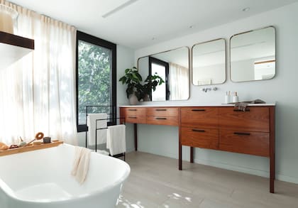 Mueble (Muchnik y Wainstein) enchapado en petiribí con mesada de Silestone y bacha incorporada. Grifería de pared (FV). Espejos hechos a medida. Toallero (Antiguo Vagón Deco). Bañadera exenta (Roca).